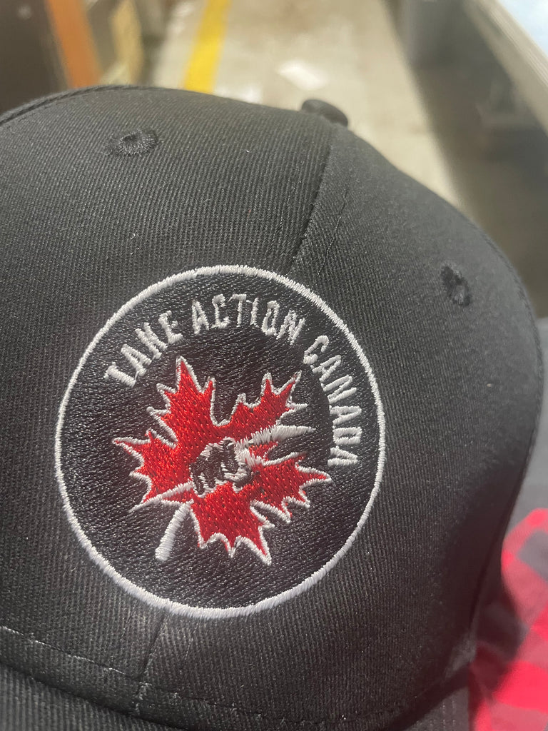 Take Action Canada embroidered on a circular patch on a baseball cap, featuring a clenched fist with a trident in the middle of a red maple leaf