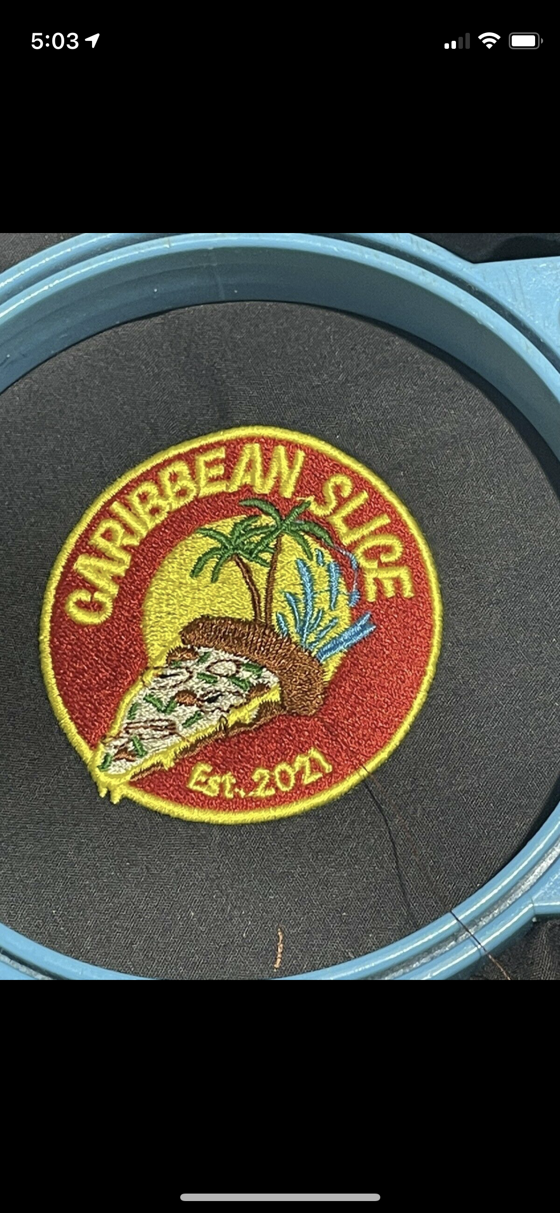 Embroidered pizza slice with palm trees and water splash in a circular patch with text Caribbean Slice Est. 2021