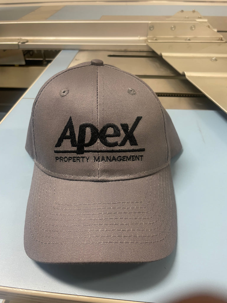 Apex Property Management Embroidered on a grey hat in black text 