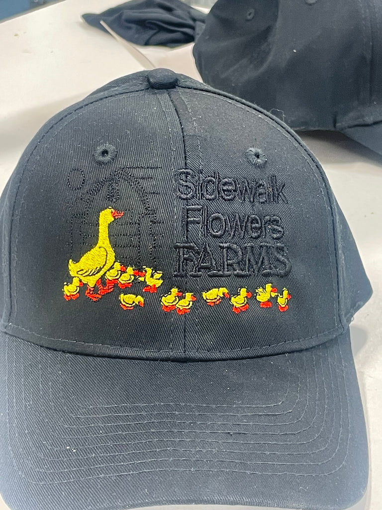Yellow Duck with ducklings embroidered on a hat walking on a farm 
